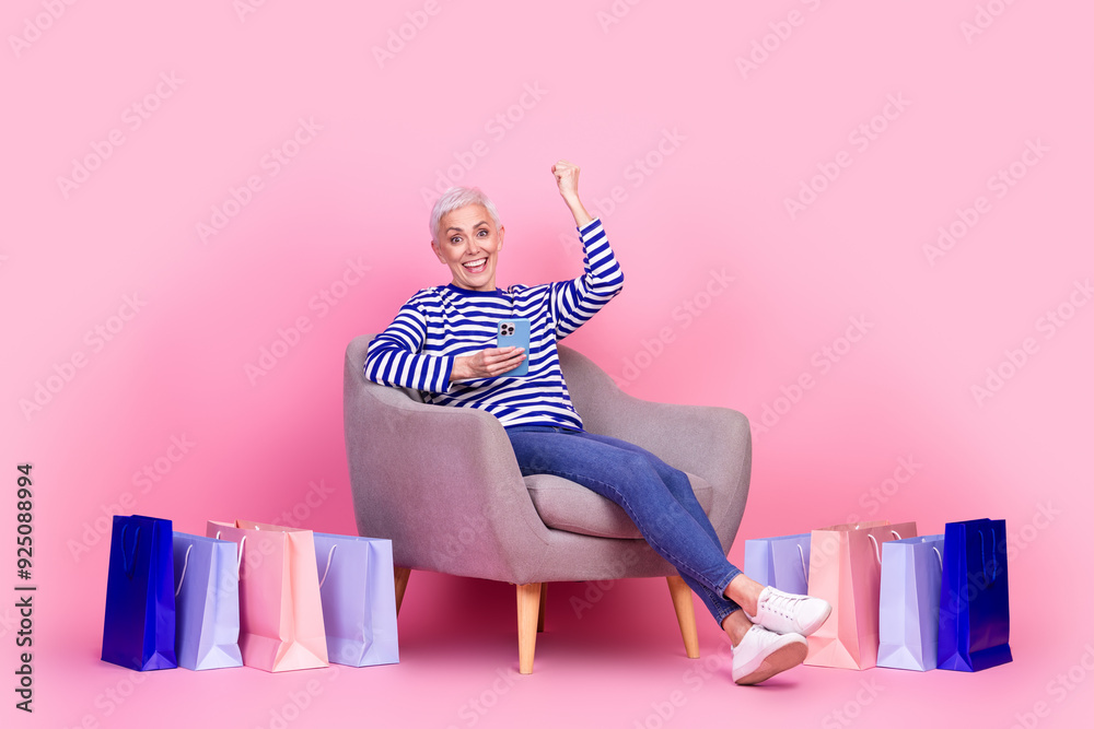 Poster Photo of charming excited crazy woman wear striped stylish clothes sit armchair rejoice sale yes isolated on pink color background