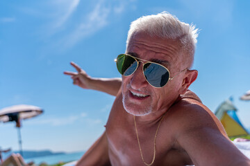 a middle aged man with white hair and goatee happy and smiling taking a selfie on summer vacation