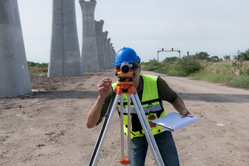 male Survey Engineer Using Leveling Camera on Construction Site: Precision and Expertise in Civil Engineering Projects. Female Land Surveyor Utilizing Leveling Camera.