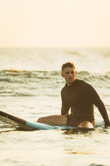 Surfer sitting on his surfboard during sunrise