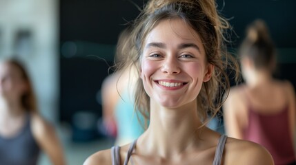 A smiling woman stands in a spacious gym, surrounded by others engaged in their fitness routines, creating an energetic and positive environment.