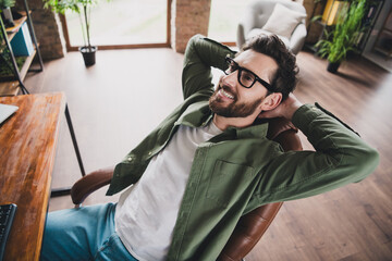 Portrait of professional hacker young man rest chair computer desk loft interior office indoors