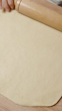 Vertical video. Flattening Dough into a Large Rectangle with a Wooden Rolling Pin, Ensuring Even Thickness.