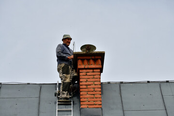 Traditional manual method of cleaning the chimney on the roof