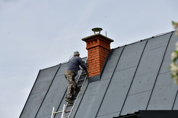 
The roof roofer climbs up the ladder to the roof of the house to fix sheet metal roof
