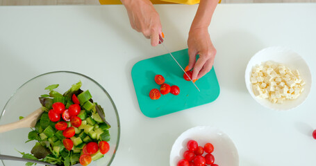 Woman slices tomatoes for a vegetable salad