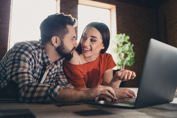 Photo of cute young couple lying floor netbook discuss online purchase enjoy weekend have fun buy new apartment indoors inside house home