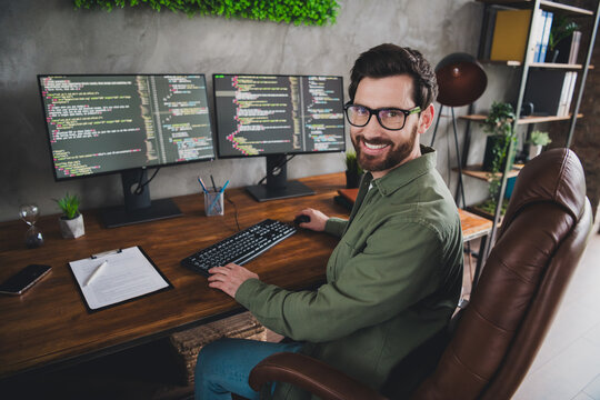 Portrait of professional hacker young man sitting chair computer desk loft interior office indoors