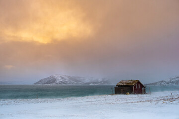 Winter Norway landscape with rorbu on the ocean beach and snow