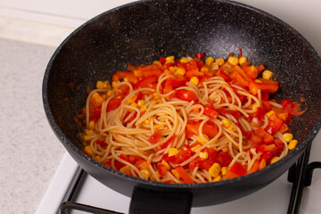 Pasta with tomato sauce in a wok on the stove.