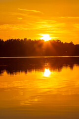 Zachód słońca nad jeziorem z odbiciem w lustrze wody