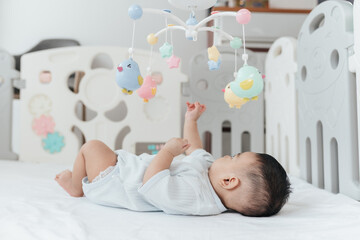 Adorable Asian Baby Boy, 5 Months Old, Smiling and Enjoy Playing with Crib Mobile in Home Playpen.