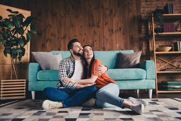 Obraz premium Full size photo of happy young couple sit floor look empty space hug move new place live together apartment room light house flat indoor