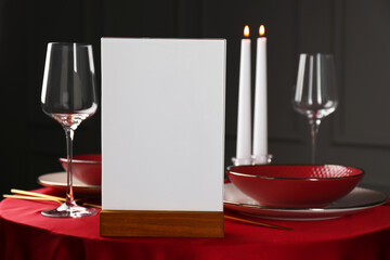 Menu holder, clean dishware and cutlery on red table in restaurant