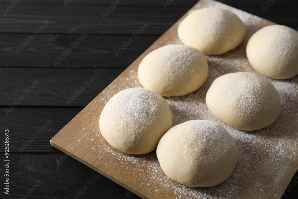 Wall mural Raw dough balls on black wooden table