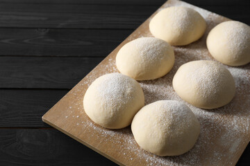 Raw dough balls on black wooden table