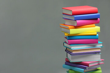 Stack of colorful books on light grey background, space for text