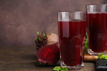 Fresh beet juice in glasses and ripe vegetables on wooden table, closeup. Space for text