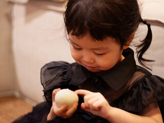 Curious asian toddler closely examining an egg