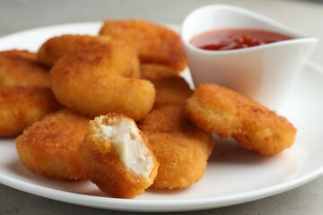 Tasty chicken nuggets with chili sauce on grey table, closeup