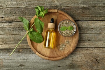 Tincture in bottle and herbs on wooden table, top view