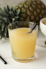 Tasty pineapple juice in glass and fresh fruit on white wooden table, closeup