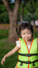 asian Toddler wearing life jacket outdoors in the park