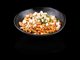 Stir-fried noodles with tofu and mushrooms in a black bowl