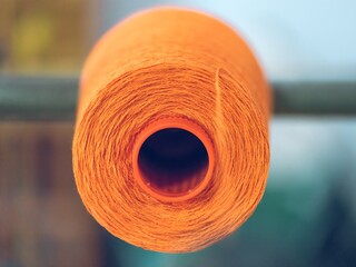 Close-up of orange yarn spool in a textile factory