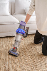 Person Using a Modern Vacuum Cleaner on Carpet © ADDICTIVE STOCK CORE