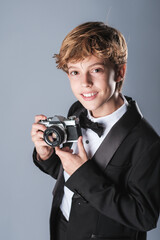 Fototapeta premium Preteen boy in elegant formal suit with bow tie and photo camera