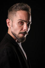 Fototapeta premium Intense man with a piercing gaze on a dark background with red contact lenses