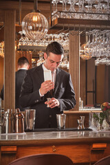 Bartender pouring syrup in jigger while preparing cocktail