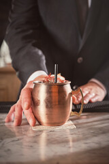 Barkeeper serving cocktail in copper mug in bar