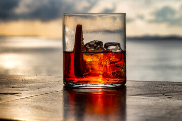 Red coctel drink photographed on the table above the sea at sunset