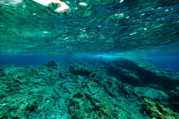 Rock formations in clean sea on sunny day