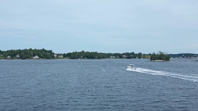 A Sisu 22 boat speeds through Boothbay Harbor, Maine, cutting through the water with ease as it leaves a wake behind in the bustling harbor.