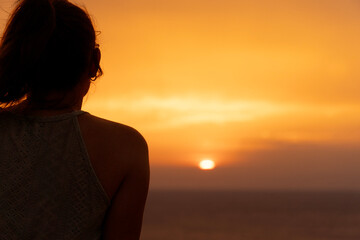 Lonely girl observes the sunset over the sea.Concept of solitude or reflection.