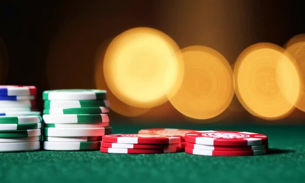 Stacks of poker chips on green felt table with bokeh lights in the background