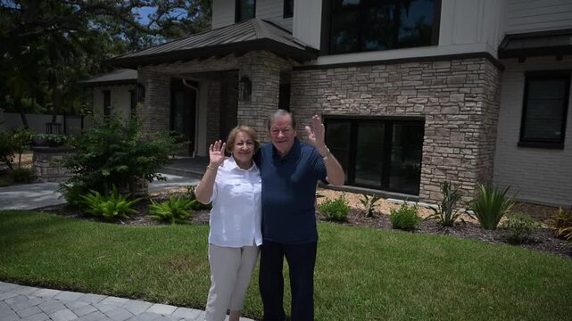 happy senior citizen couple smiling and waving in front of the house as if they are pleased with services