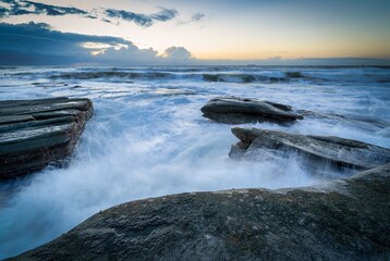 Serene sunrise over a beach with rocks and bubbling waters