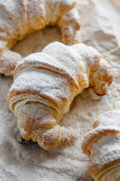 Croissant sprinkled with powdered sugar, close-up. 