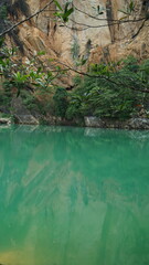 An image of a peaceful emerald-green lake with a backdrop of rocky cliffs and lush greenery.