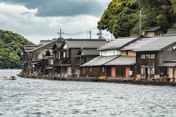 Obraz premium Beautiful scenic view with the wooden traditional waterfront boat houses called funaya around Ine Bay, in the village Ine, Japan