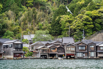 Fototapeta premium Beautiful scenic view with the wooden traditional waterfront boat houses called funaya around Ine Bay, in the village Ine, Japan