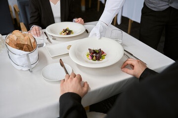 Waiter serving order to table for man and woman on date in a restaurant