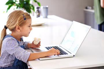 Child, laptop and reading in kitchen for education, online and internet for e learning at table. Kid, snack and screen or social media in home for streaming, digital app and website for communication