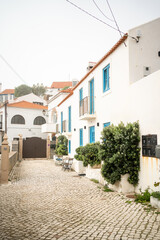 Typical street in Portugal surrounded by white two-storey houses. Small Portugal city Azenhas do Mar with beautiful houses. Shot passing by white big houses on narrow street.