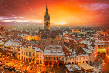 Obraz premium Winter atmosphere in Sibiu, Romania. Discover a winter wonderland of snow-covered medieval architecture, twinkling lights, and festive charm in this historic Transylvanian city.