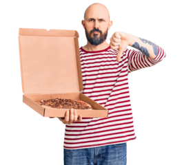 Young handsome man holding delivery pizza box with angry face, negative sign showing dislike with thumbs down, rejection concept